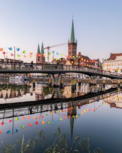 Travefloden om aftenen med en bro i forgrunden og kirker bagved