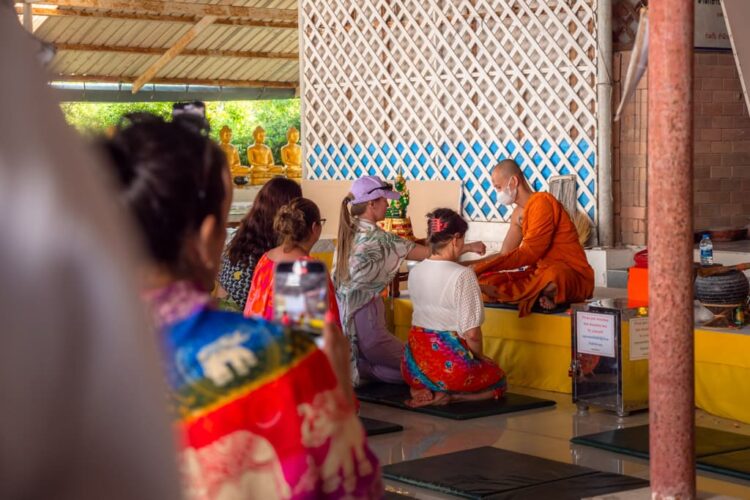 Turister bliver velsignet af en munk for en donation til templet