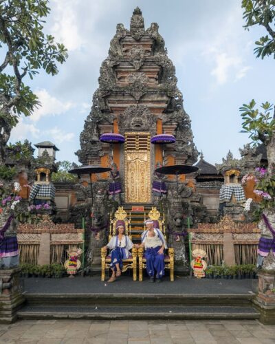 Alex og Victoria med tempeltøj siddende på stole i Pura Taman Saraswati