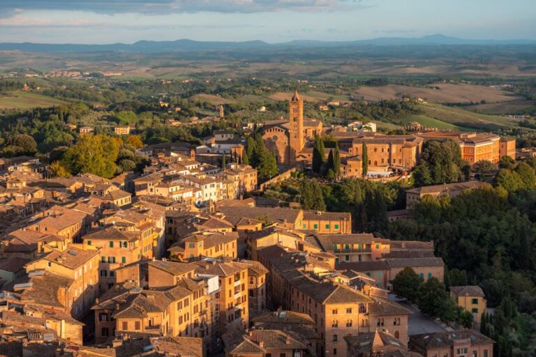 Huse i Siena med det toscanske landskab med bakker i baggrunden - set fra Torre del Mangia