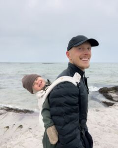 Alexander med sin søn Adrian på ryggen i en bæresæle med sælerne i baggrunden